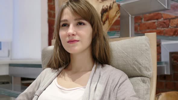 Portrait of Serious Young Woman Sitting on Relaxing Chair