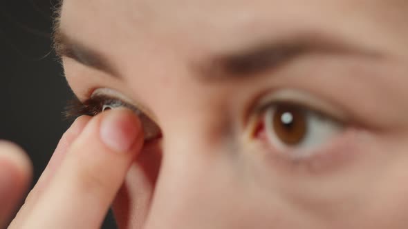 Closeup of Brown Eye Young Woman Taking Off Blue Lens