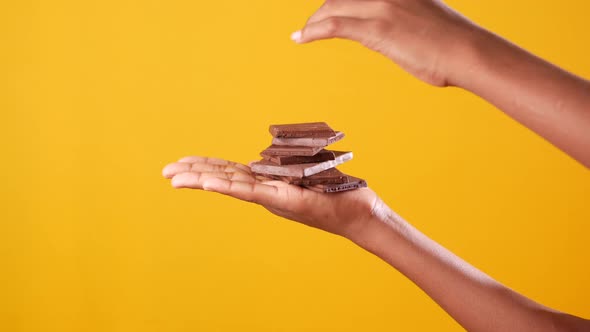 Holding Stack of Chocolate Against Yellow Background