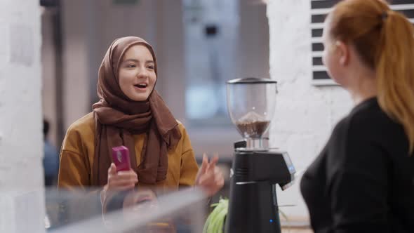 Positive Young Beautiful Muslim Woman Making Order in Coffee House