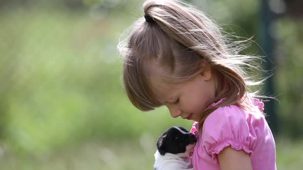 Pretty Child Girl Playing with Little Puppy Outdoors in Summer