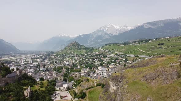 Drone flight between two hills with castles in green Switzerland with beautiful sunny weather (Sion,