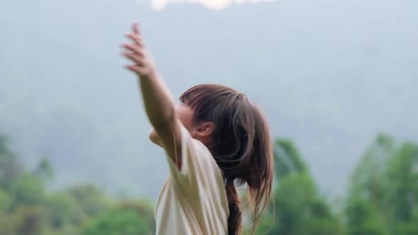 Cute little girl having fun catching rain drops. Kids play in summer rain. Child playing outdoor.