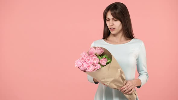 Portrait of Displeased Woman 20s with Long Brown Hair Looking at Bouquet of Tulips and Expressing