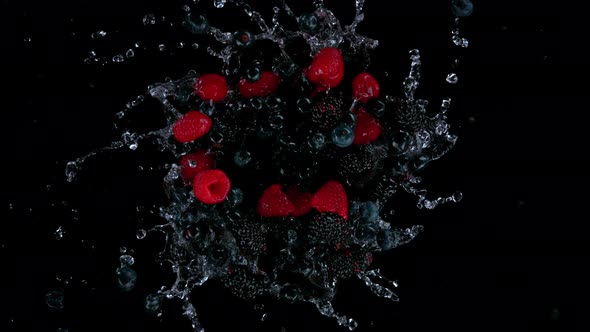 Super Slow Motion Shot of Rotating Exploded Berries Fruit with Splashing Water on Black at 1000Fps