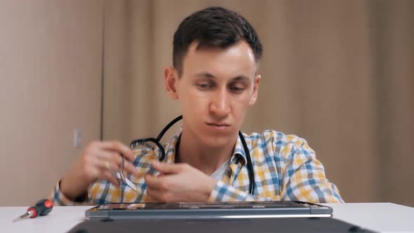 Repairman Removes the Laptop Cover and Listens with a Phonendoscope