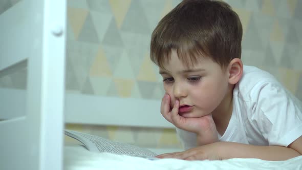 a Seven Year Old Boy Reads a Book in His Bed Before Going To Bed