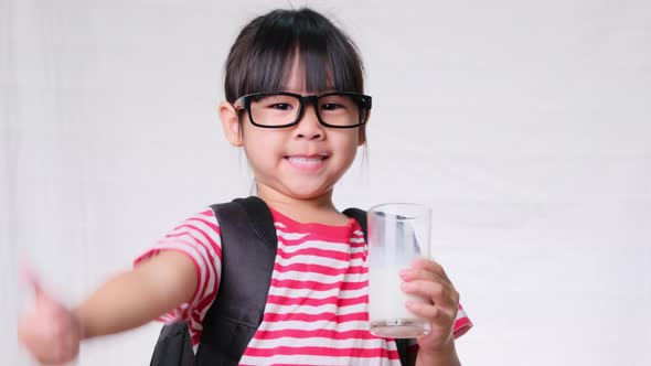 Cute schoolgirl drinking milk from a glass before going to school. Healthy nutrition for children. b alt