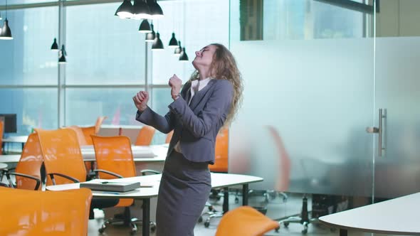 Joyful Excited Beautiful Slim Woman Dancing in Office Indoors Smiling