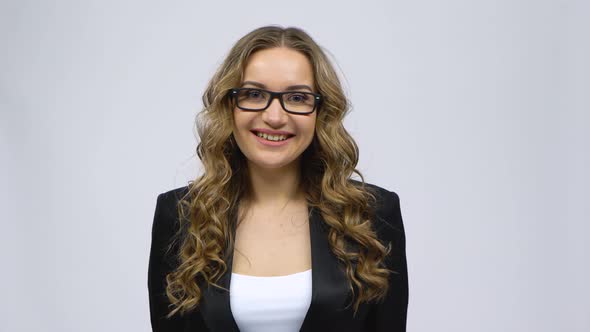 Business Woman Coquettishly Smiling While Looking at Camera on Gray Background