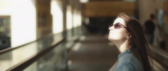 Woman with sunglasses looking around while standing on a moving walkway