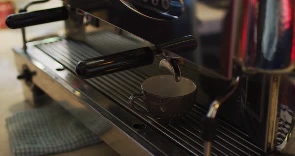 Midsection of african american male barista making coffee in coffee machine