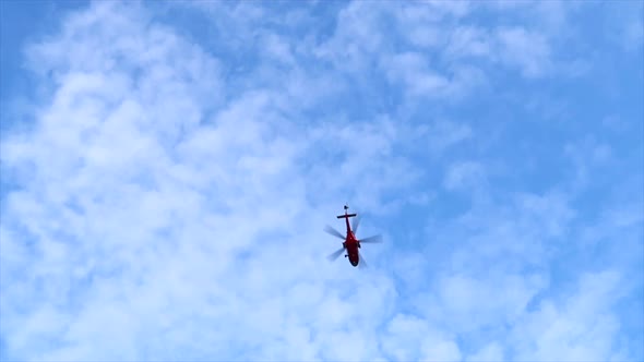 helicopter passing by from low angle in blue cloudy sky