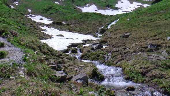 Waterfall in a valley flows under the snow.