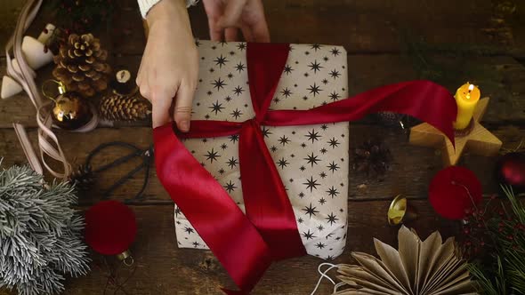 Hands wrapping stylish cChristmas gift with red ribbon