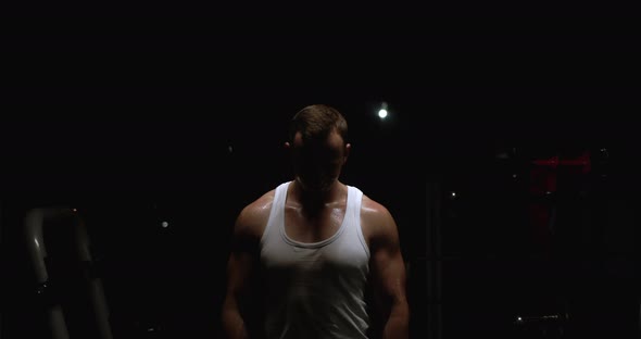 A man in the gym breathes deeply after exercise, his body is covered with beads of sweat