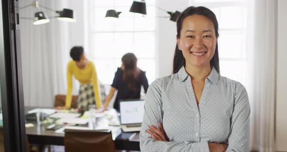 Happy asian businesswoman standing in office and looking at camera