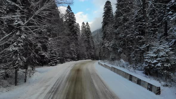 Aerial View Mountain Road Through Snowy Coniferous Forest in Winter