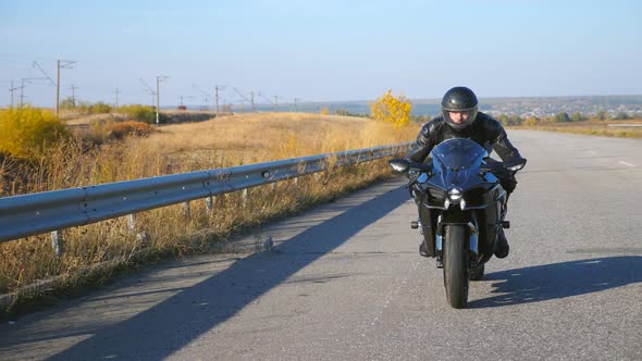 Young Man Riding on Modern Sport Motorbike at Autumn Highway