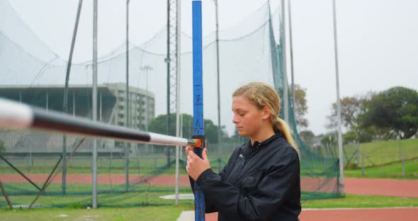 Front view of Caucasian female athlete checking high jump bar at sports venue 4k