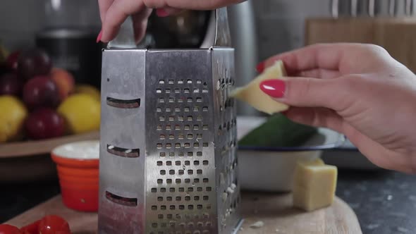 Woman grating cheese on wooden chopping board. Slow zoom out