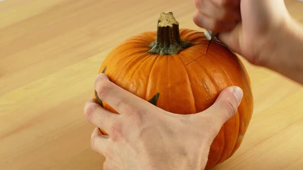 A man cleans and carves the eyes and mouth of a pumpkin in preparation for Halloween