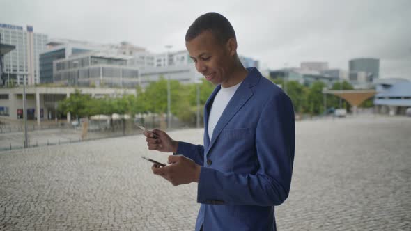 Smiling Young Man Holding Credit Card and Smartphone Outdoor