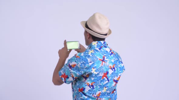 Rear View of Young Happy Hispanic Tourist Man Taking Picture with Phone