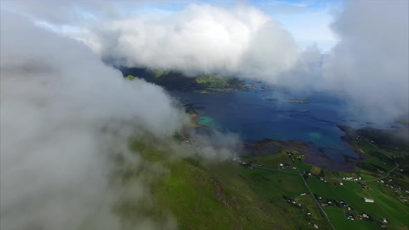 Fast moving clouds on green mountain top, aerial view