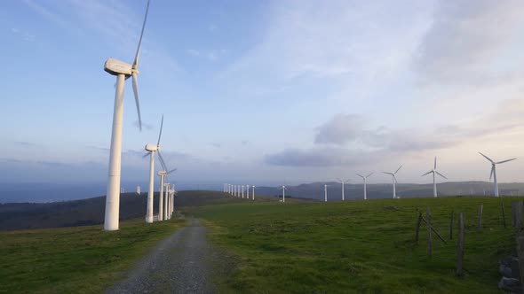 Wind turbines renewable energy at sunset with blue sky and green landscape in Spain