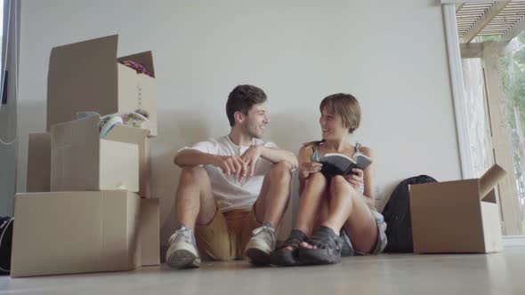 Couple sitting on floor amongst cardboard boxes