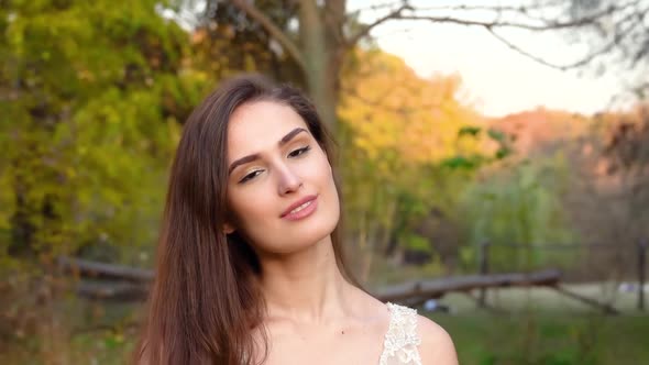 Beautiful Woman Is Posing at the Sunset Against Autumn Nature. Video Shooting Movement Camera with