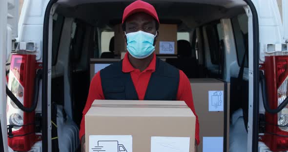 African man courier delivering packages with truck while wearing safety face mask