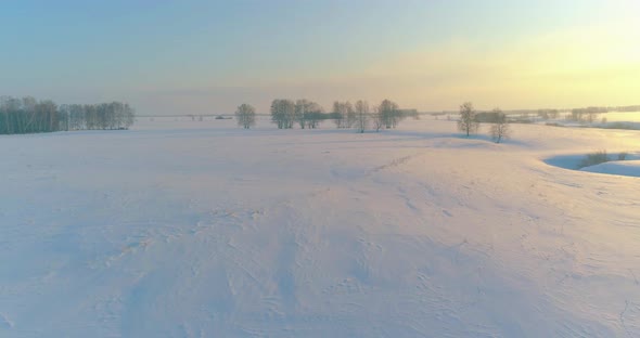 Aerial View of Cold Arctic Field Landscape Trees with Frost Snow Ice River and Sun Rays Over Horizon