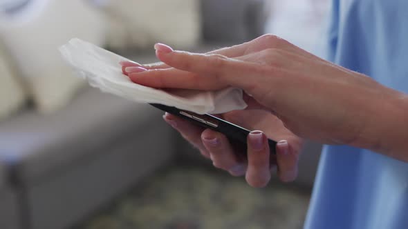 Mid section of Female health worker wiping her smartphone with a tissue