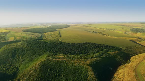 Aerial drone view of nature in Moldova. Valley with green hill slopes, fields, village