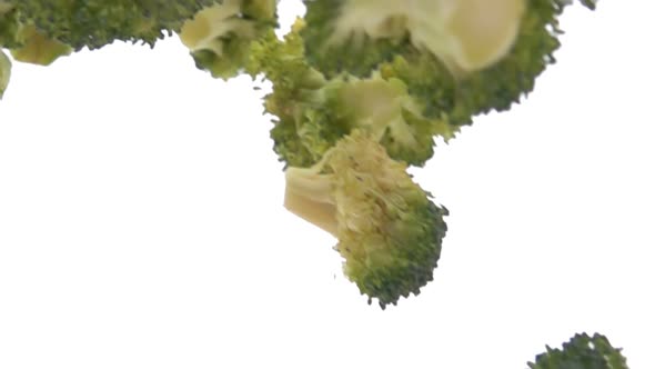 Closeup of the Green Fresh Broccolli Pieces Falling Diagonally in Slow Motion