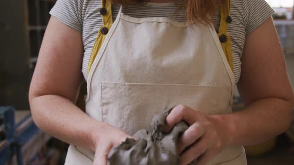 Portrait of female potter wearing face mask and apron working on clay at pottery studio