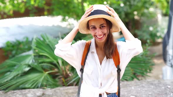 Beautiful Joyful Tourist Woman in Straw Hat and White Shirt Looking and Smiling at Camera