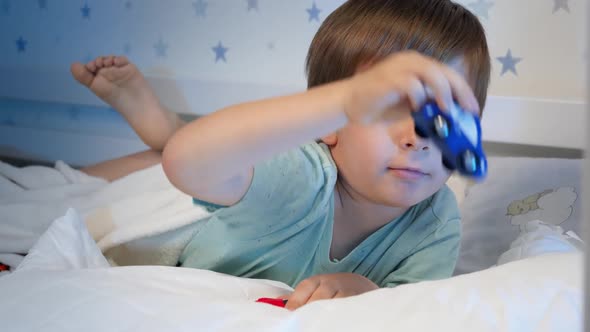 Portrait of Little Boy Playing with Two Toy Cars at Bedtime