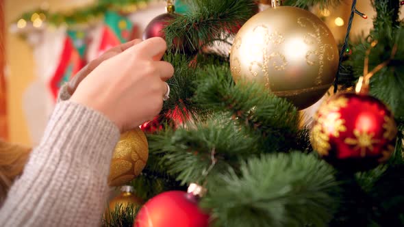 Closeup Footage of Camera Panning Over Christmas Tree While Young Woman in Wool Sweater Decorating