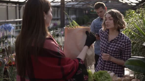 A Young Girl Purchasing Organic Food in Local Greenhouse Recieving Her Grocery in Paper Bag and Pay