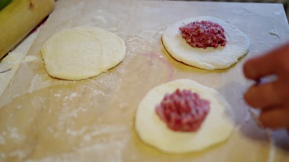 Female Hands Fold the Meat Filling Into the Dough for Pies