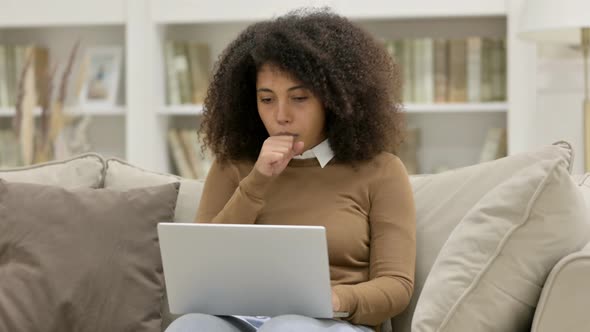 Young African Woman with Laptop Coughing on Sofa