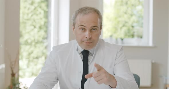 Serious Strict Doctor with Finger Raised Talking at Camera. Portrait of Confident Caucasian