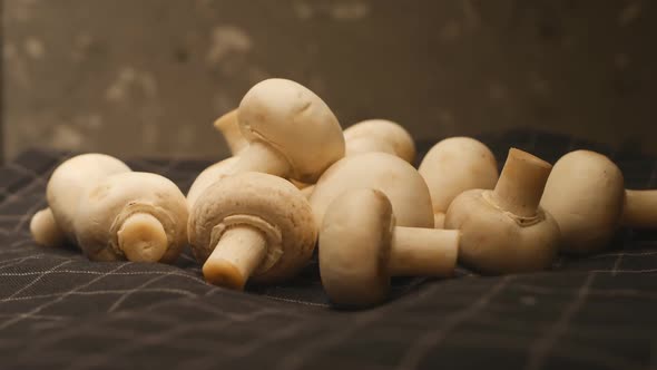 a Bunch of Whole Champignon Mushrooms Rotate Closeup While Being on a Dark Checkered Fabric