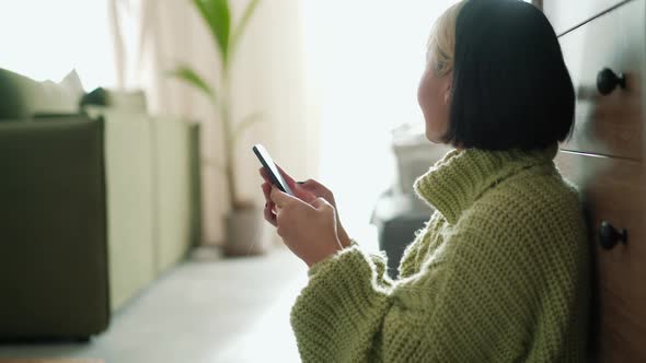 Side view of positive Asian woman looking at phone