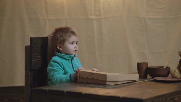 Cute Boy Eating Pizza at Home. Funny Boy Open Box a Big Pizza.