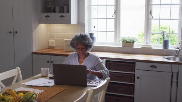 Senior african american woman using laptop and calculating finances at home