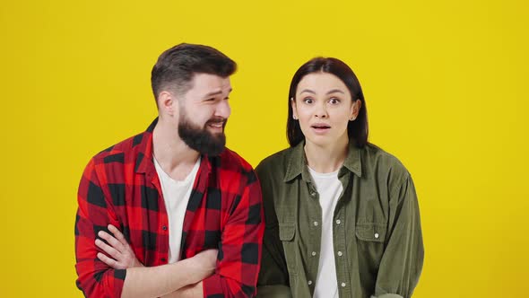 Portrait of Shocked Couple Against Yellow Background